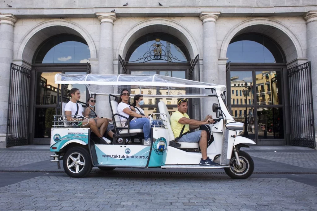 Un tuk tuk, en el que los ocupantes van, en su mayoría sin mascarilla, frente al Teatro Real (Fuente: Agencias)