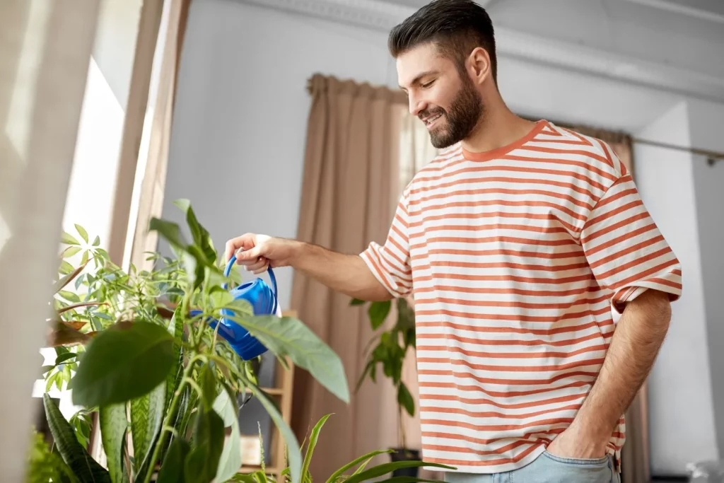 ¿Cómo debo dejar las plantas al irme de vacaciones para que me las encuentre bien? 8 Moncloa hombre feliz sonriente regando flores en casa Moncloa