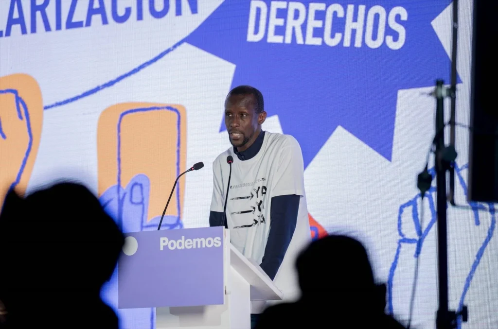 El secretario de antirracismo de Podemos, Serigne Mbayé, interviene durante el acto ‘Regularización son derechos’ (Fuente: Agencias)