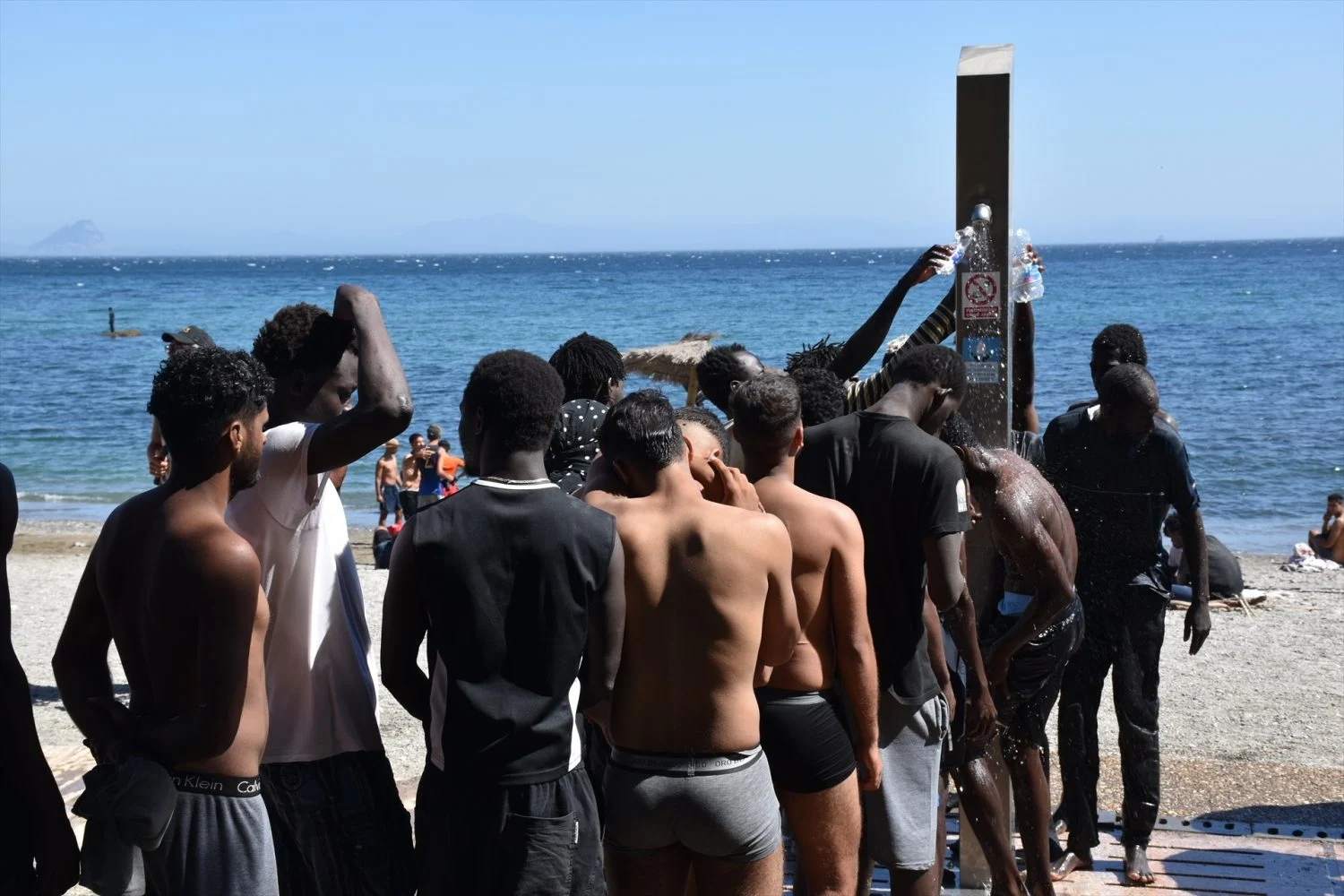 Varias personas se asean en las duchas públicas, en la playa del Trampolín Varios migrantes se asean en las duchas públicas, en la playa del Trampolín. Foto: Europa Press.