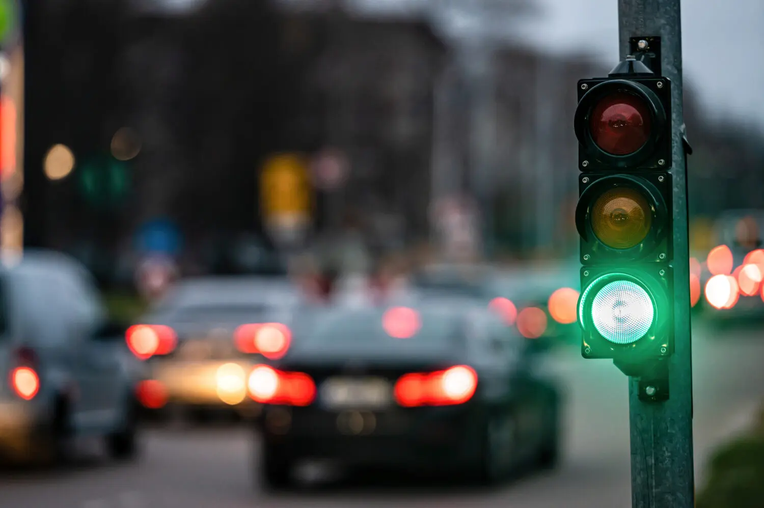 un-cruce-de-la-ciudad-con-un-semaforo-en-el-fondo-borroso-con-coches-en-las-calles-de-la-noche-luz-verde