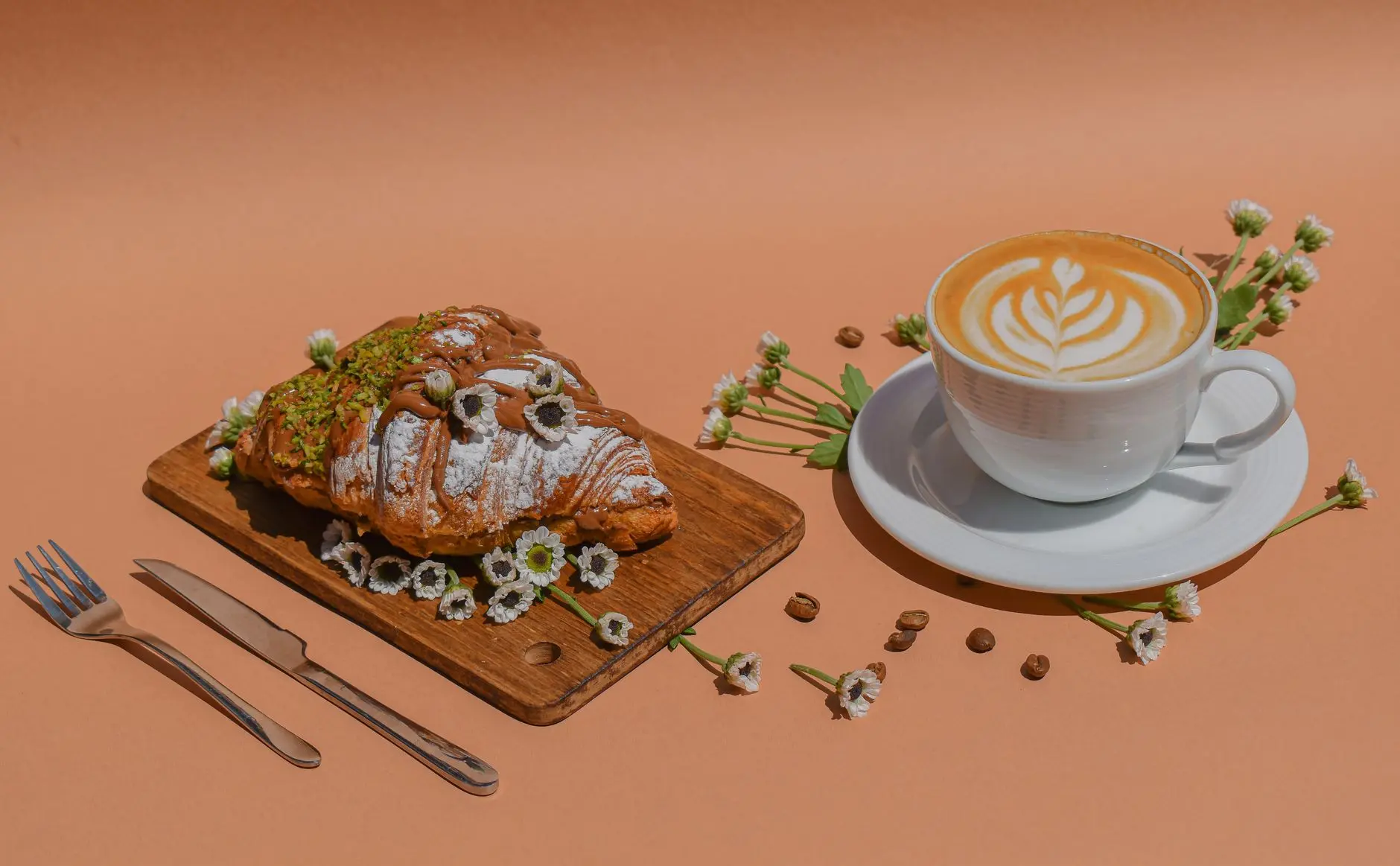 Estilo de café y croissant con flores y granos de café en una tabla de madera.