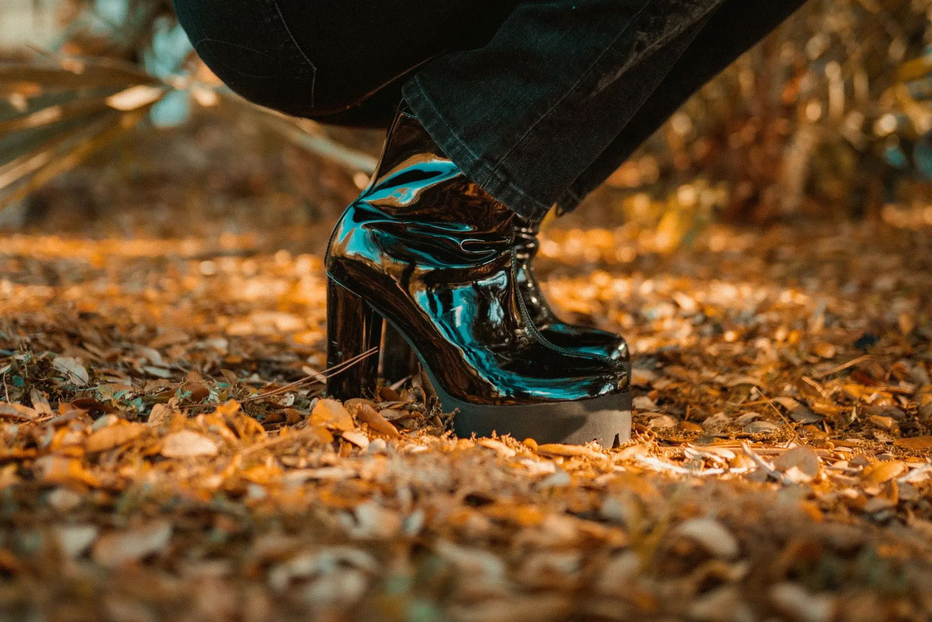 Acercamiento de botas negras brillantes sobre hojas de otoño en Winter Park, Florida.