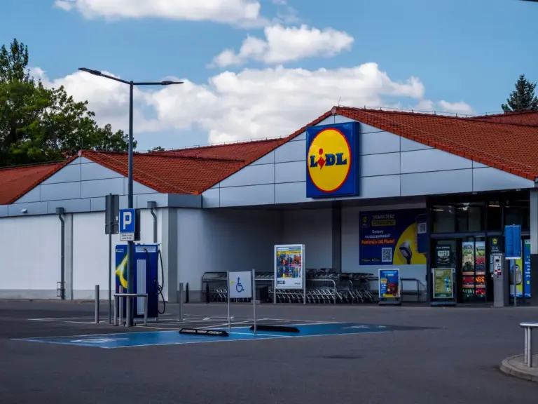 Exterior del supermercado Lidl con área de estacionamiento y carros de compras en un día soleado.