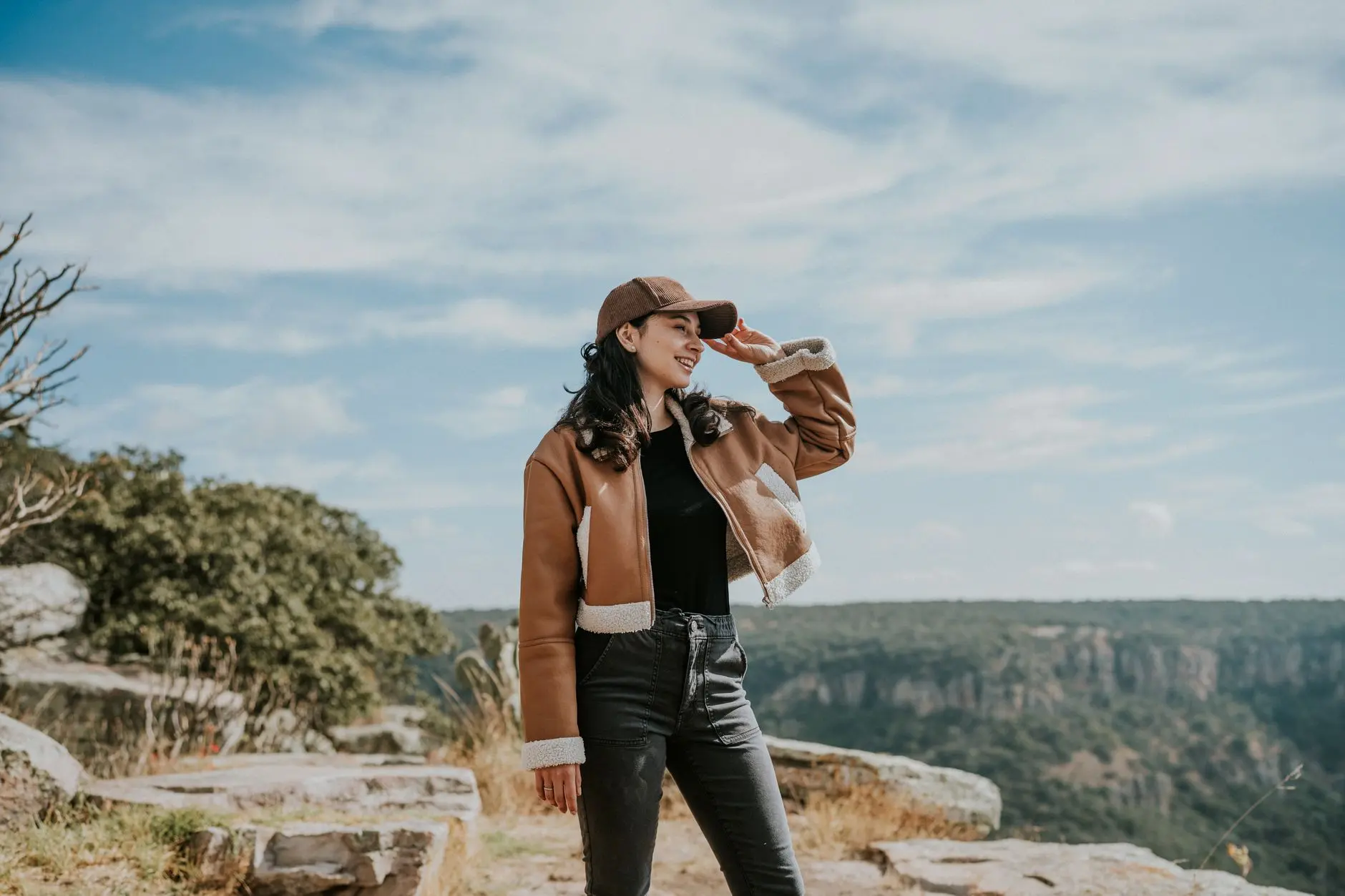 Mujer joven con ropa casual disfrutando de una vista escénica de la montaña en un día soleado.