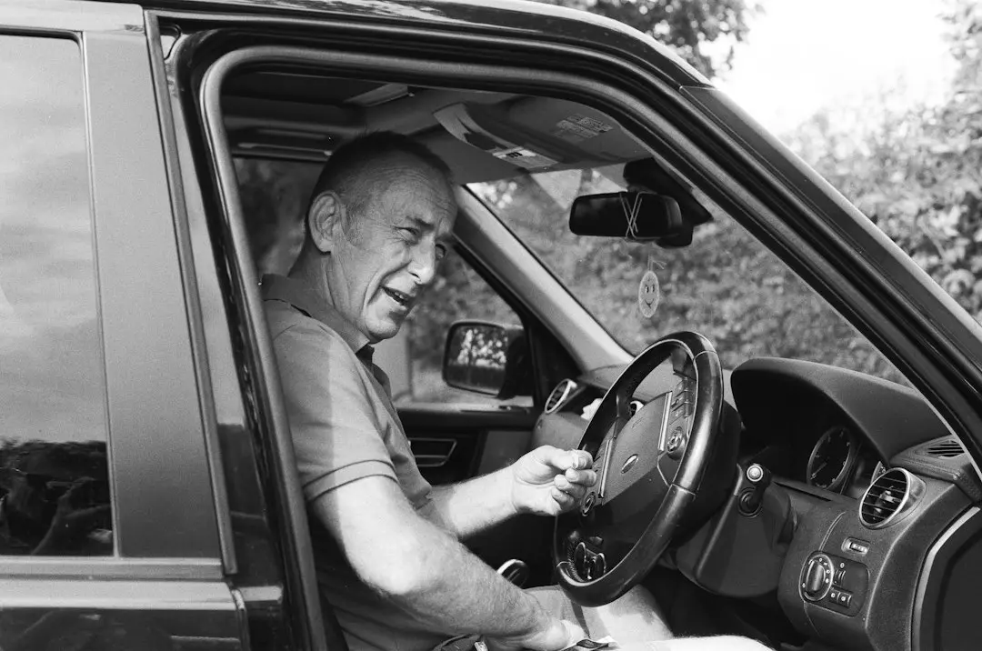 man in gray polo shirt driving car